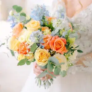 Bride holding a coral and pale blue bridal bouquet