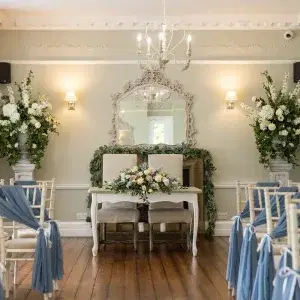 Wedding ceremony room with white chairs with powder blue chiffon sashes and blue and white table flower display